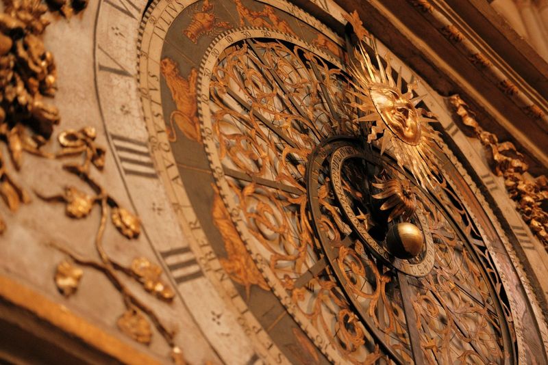 Ornate gilded astronomical clock face with zodiac figures and a golden sun